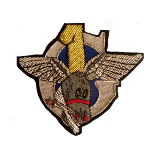 Silver 'C' intersected with yellow number 1 and winged donkey head holding a Kukri knife in its mouth
