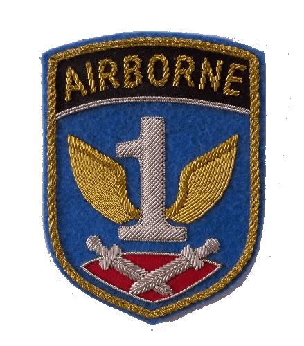 Silver 1 with gold wings in center of blue shield shaped patch with crossed daggers lying on a red cushion below and word AIRBORNE at top of patch