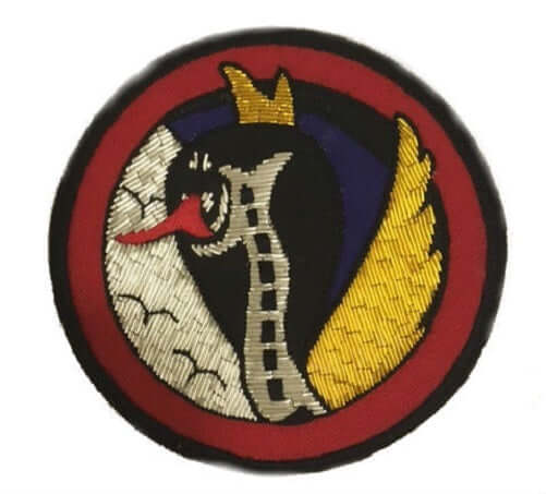 Circle shaped patch with silver, blue and gold background and red outer ring. Crown-wearing snake in center with red tongue.
