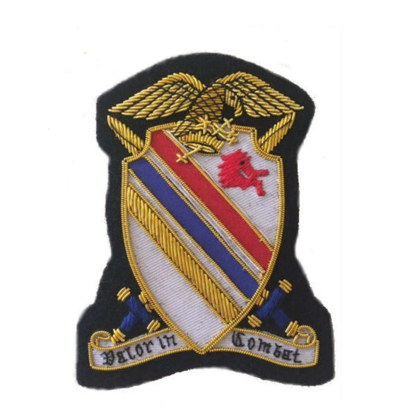 White shield shaped patch with red, blue, gold diagonal stripes running from top right to bottom left and two crossed swords under the shield. Red horse head on top left of shield. Gold eagle sitting on top of the shield and ribbon banner along bottom with words ' Valor in Combat'