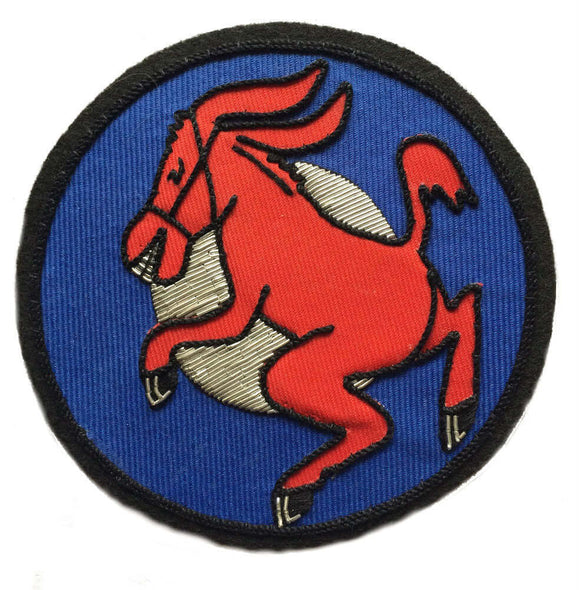 Blue circle shaped patch with silver inner circle. Red dancing donkey facing right, embroidered in center.