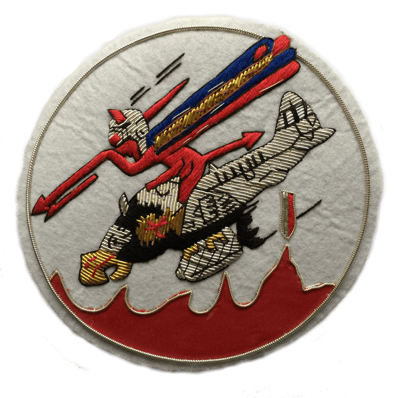 White circle shaped patch. With Red devil character riding on a plane with a bird's head, and holding a red spear. Bomb dropping from under the plane.