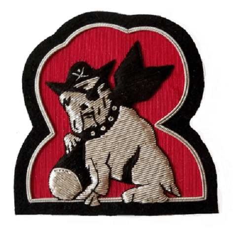 Red background with black outer edge. In center is silver bulldog wearing a pirates hat and black patch over left eye and holding a missile