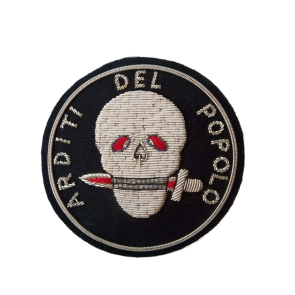 Black circle shaped patch with silver skull in center. Skull holds dagger in teeth. Words 'Arditi del Popolo' around outer edge
