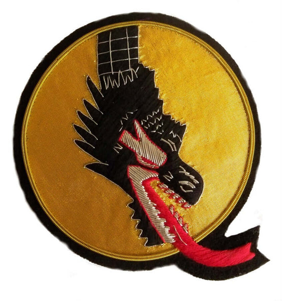 Gold oval shaped patch with black dragon head and neck coming from top of patch. Dragon mouth is open and spitting red fire