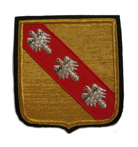 Gold color rectangle shaped patch with red ribbon running diagonally top right to bottom left, with three silver birds on it.