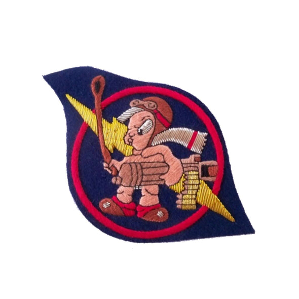 Dark blue eye shaped patch with cartoon character standing in center, wearing a flying helmet, goggles and silver scarf and holding a machine gun under his arm