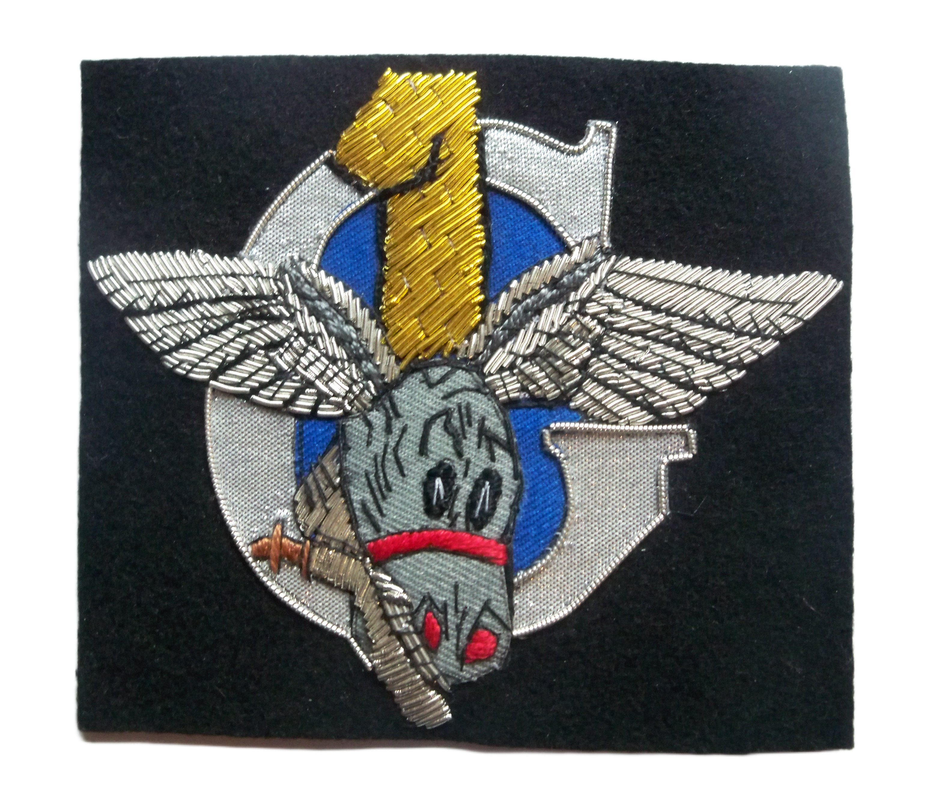 Bullion embroidered patch of donkey with wings for ears, holding a Kukri in its mouth. On a Silver G for glider and gold number 1.