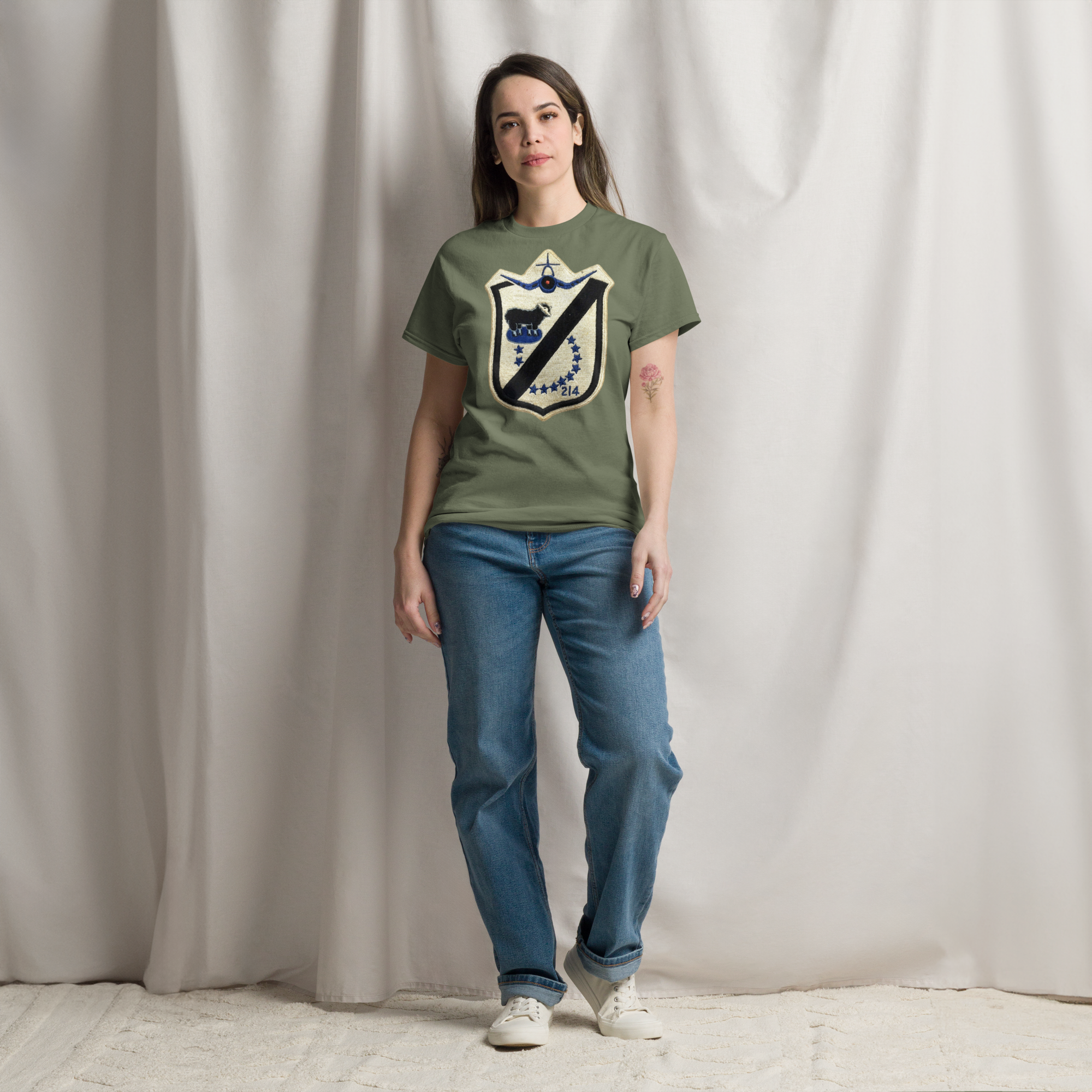 Girl wearing army green short sleeved tee shirt with Black Sheep patch on the front in cream and black.