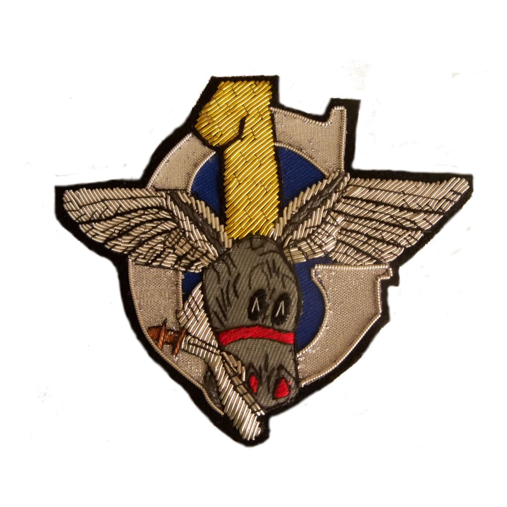 Silver 'C' intersected with yellow number 1 and winged donkey head holding a Kukri knife in its mouth