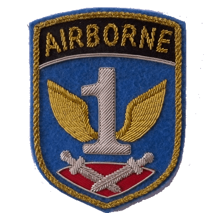 Silver 1 with gold wings in center of blue shield shaped patch with crossed daggers lying on a red cushion below and word AIRBORNE at top of patch