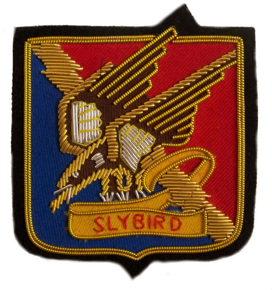 Square shaped patch with gold and silver bird embroidered on blue and red background, with word 'Slybird' under bird