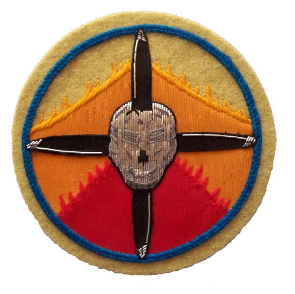 Circle shaped patch with yellow orange red sunrise background.  Silver skull in center on crossed black propellers