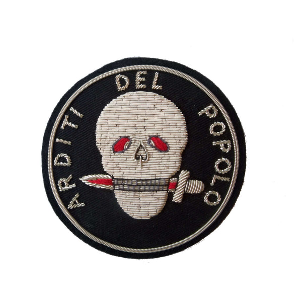 Black circle shaped patch with silver skull in center.  Skull holds dagger in teeth.  Words 'Arditi del Popolo' around outer edge