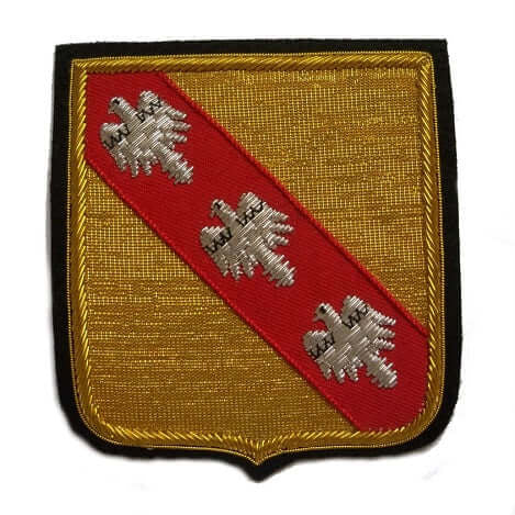 Gold color rectangle shaped patch with red ribbon running diagonally top right to bottom left, with three silver birds on it.