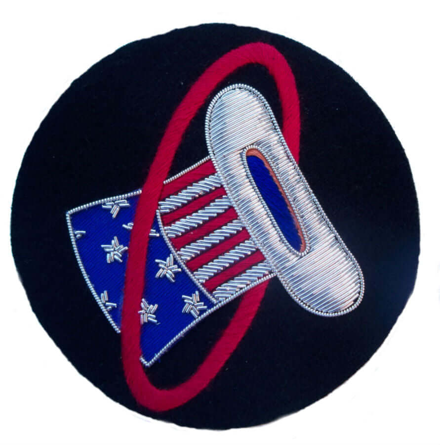 Black circle shaped patch.  In center is red ring with top hat going through it.  Top hat has stars and stripes and white brim.